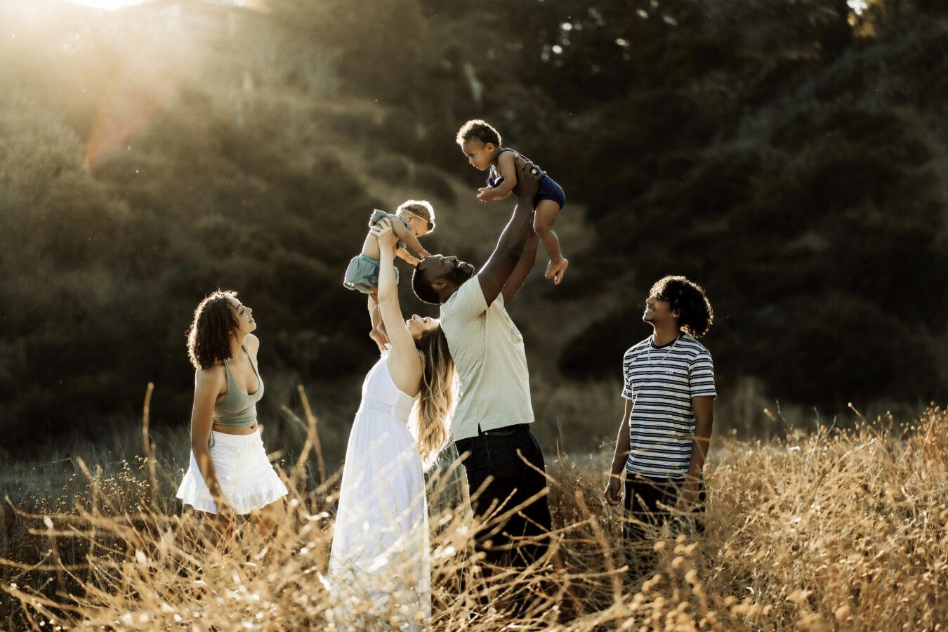 mixed race family portrait of mom, dad, and 4 children in grassy field during golden hour. Photo by czarina luna.