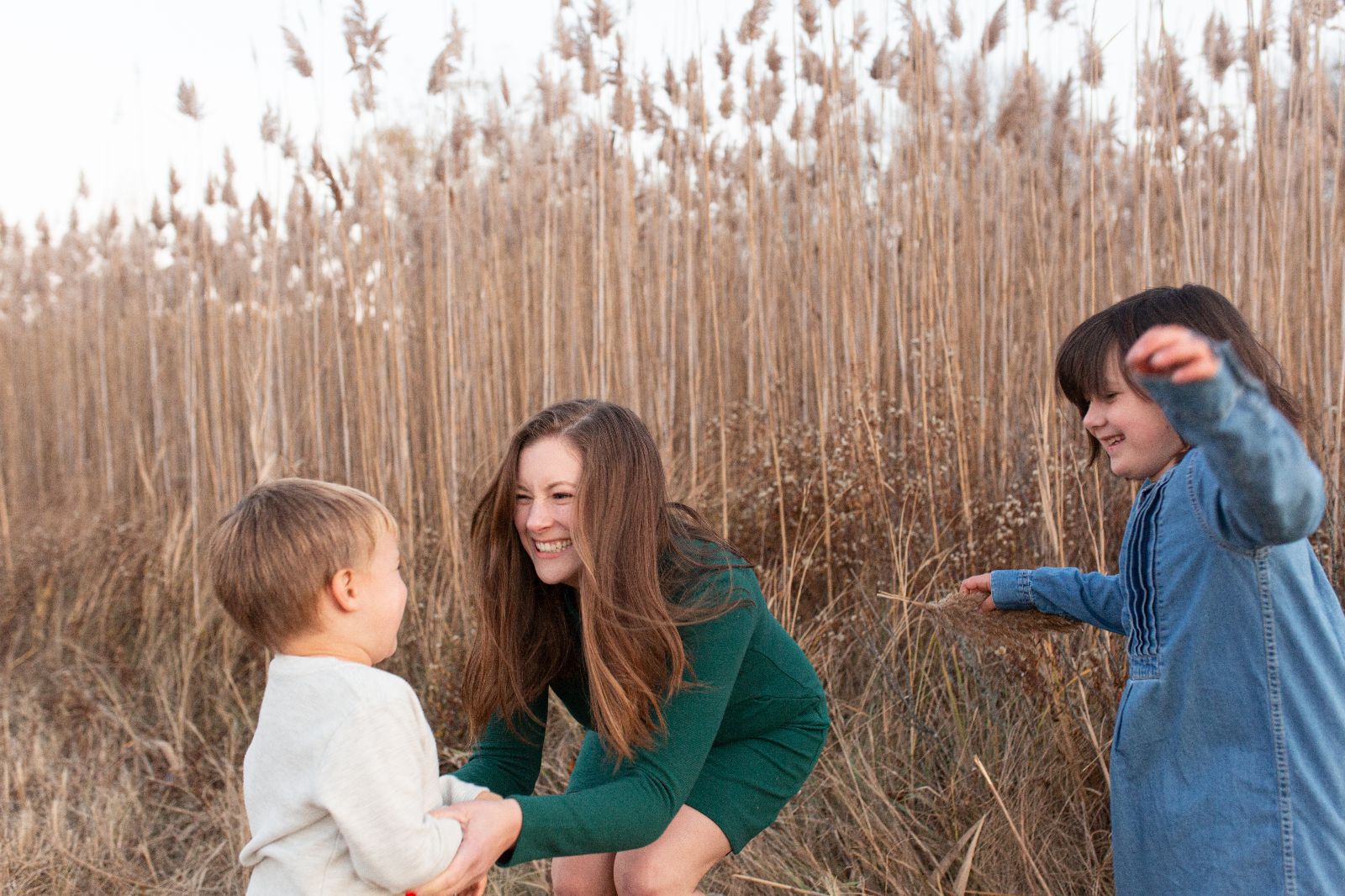 mother with two children in autumn near tall beige ornamental grasses